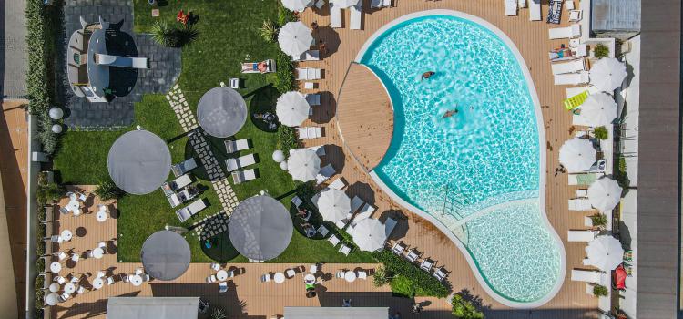 Vista dall'alto di piscina e giardino, atmosfera estiva e rilassante.